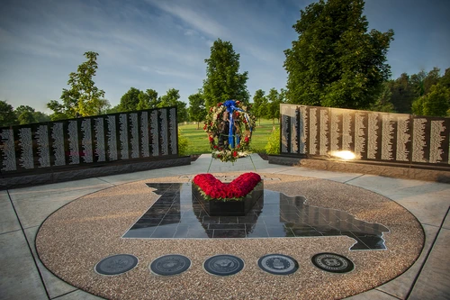 Photograph of a black granite memorial and red roses in a wreath